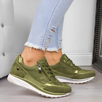 Jeans déchirés bleu clair et baskets vertes brillantes pour femme, posées sur un sol en bois, style décontracté et moderne.
