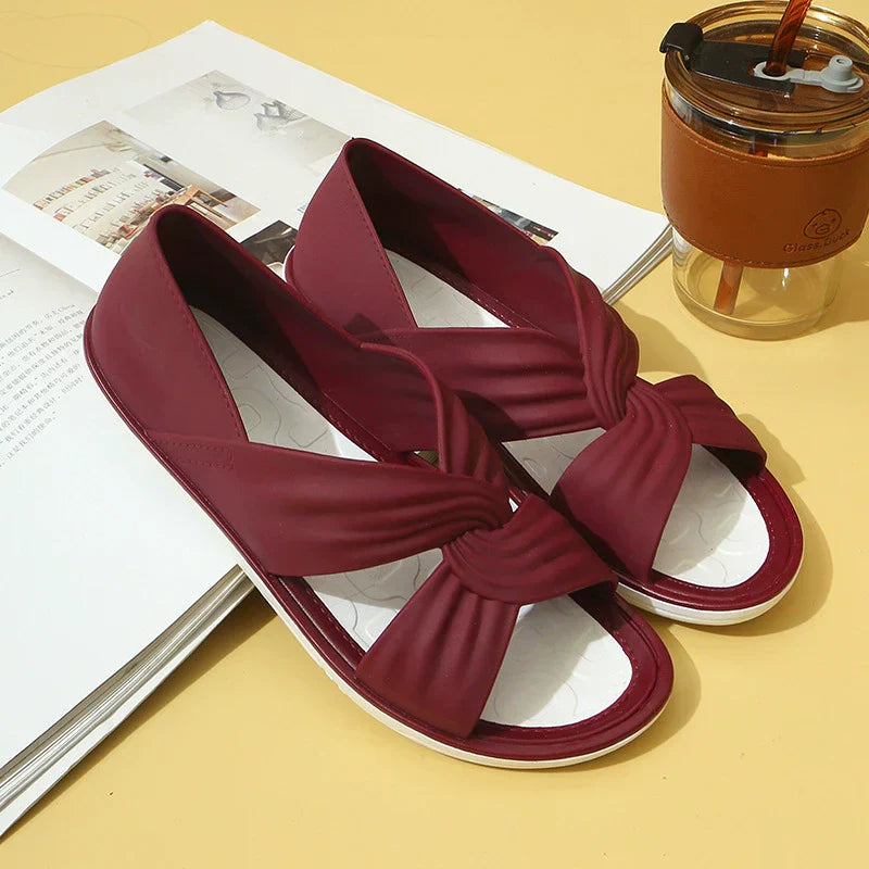 Sandales rouges élégantes avec nœud, posées sur un livre ouvert, à côté d'une tasse de café réutilisable. Mode féminine, accessoires d'été.