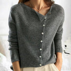 Femme portant un pull en laine gris avec boutons asymétriques, manches longues, col en V, style décontracté. Mode automne-hiver élégante.