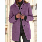 Manteau femme violet élégant, col montant, boutons noirs, poches avant, porté sur pull gris et jean noir, mode automne-hiver tendance.