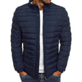 Homme portant une doudoune bleu marine, matelassée, avec fermeture éclair, sur un t-shirt blanc et un jean. Mode masculine, veste hiver tendance.