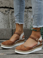 Sandales compensées marron en daim avec bride cheville, semelle en corde tressée, portées avec un jean déchiré. Mode estivale tendance.