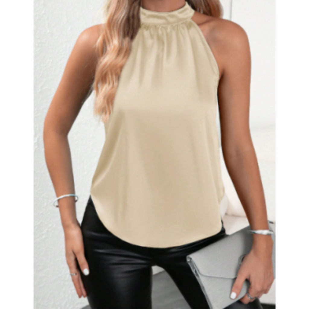 Femme portant un haut sans manches beige élégant, pantalon noir en cuir, tenant une pochette grise. Mode chic, tenue décontractée, style moderne.