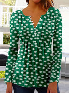 Femme portant un haut vert à manches longues avec motif floral blanc, col en V et boutons. Mode féminine, style décontracté, tendance printemps.