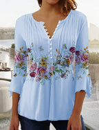Blouse bleue à manches longues avec boutons, ornée de motifs floraux colorés et papillons. Style décontracté, idéal pour le printemps et l'été.