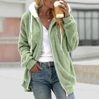 Femme portant un manteau en polaire vert avec capuche, tenant un café à emporter. Mode décontractée, tendance automne, style urbain.