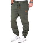 Pantalon de jogging vert kaki pour homme, avec cordon de serrage blanc et baskets blanches. Mode décontractée, style urbain, confort.