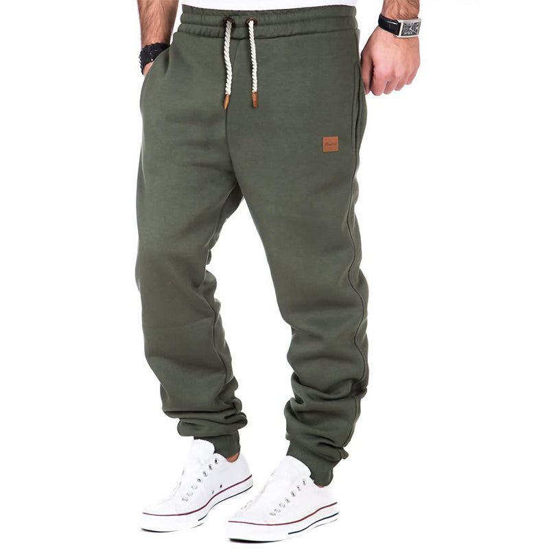 Pantalon de jogging vert kaki pour homme, avec cordon de serrage blanc et baskets blanches. Mode décontractée, style urbain, confort.