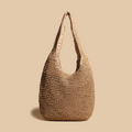Sac en paille tressée beige sur fond uni, style bohème chic, idéal pour l'été. Accessoire mode tendance, éco-responsable et spacieux.