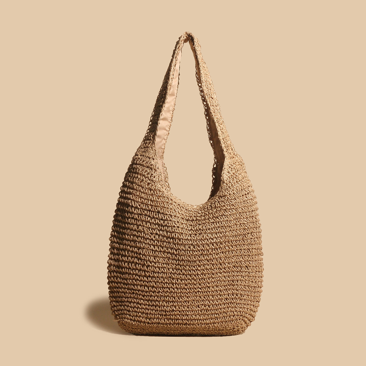 Sac en paille tressée beige sur fond uni, style bohème chic, idéal pour l'été. Accessoire mode tendance, éco-responsable et spacieux.
