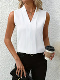 Femme en chemisier blanc élégant, tenant un café à emporter et une pochette noire, posant devant un mur texturé. Mode chic et moderne.