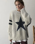Femme portant un pull en laine beige avec étoile noire et rayures, style décontracté, mode automne-hiver, tendance vêtements chauds.