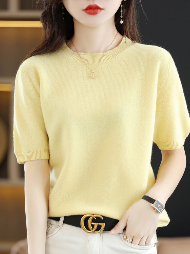 Femme portant un pull jaune en cachemire, ceinture noire avec boucle dorée, montre élégante et boucles d'oreilles pendantes, mode chic et tendance.