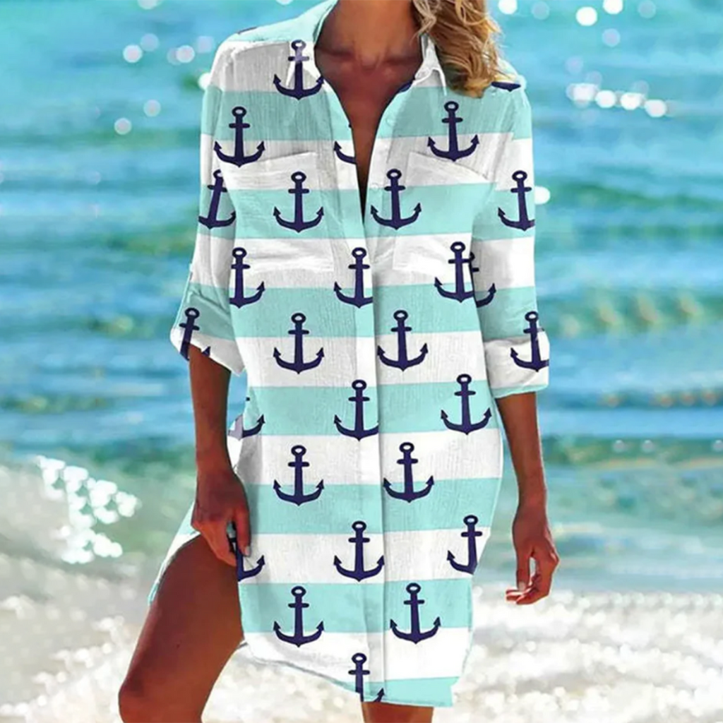 Robe de plage à motifs d'ancres marines bleues et blanches, manches longues, sur fond de mer et de vagues, style estival décontracté.