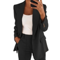 Femme en costume noir élégant, tenant un smartphone, portant un débardeur blanc. Mode professionnelle, tenue chic, style moderne.