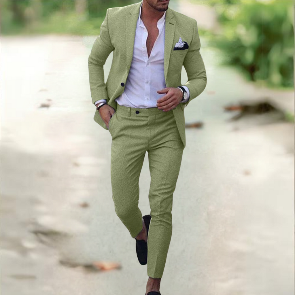 Homme en costume vert clair, chemise blanche, marchant sur un chemin extérieur. Mode masculine élégante, tenue décontractée chic, style moderne.
