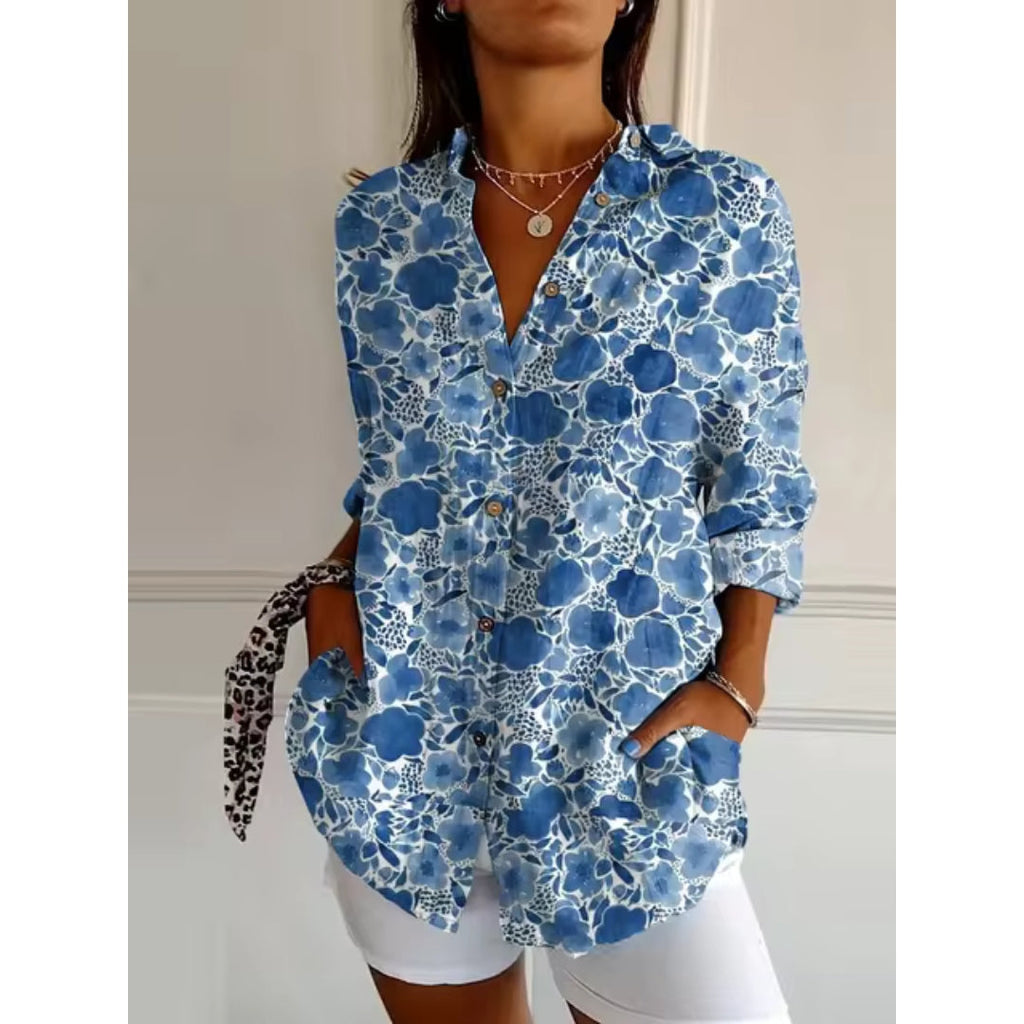 Chemise femme à motifs floraux bleus, manches longues, col ouvert, portée avec short blanc. Style décontracté et tendance pour l'été.
