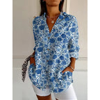 Chemise femme à motifs floraux bleus, manches longues, col ouvert, portée avec short blanc. Style décontracté et tendance pour l'été.