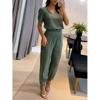 Femme en tenue verte élégante, posant devant un miroir. Ensemble pantalon et haut chic, intérieur moderne. Mode féminine, style décontracté.