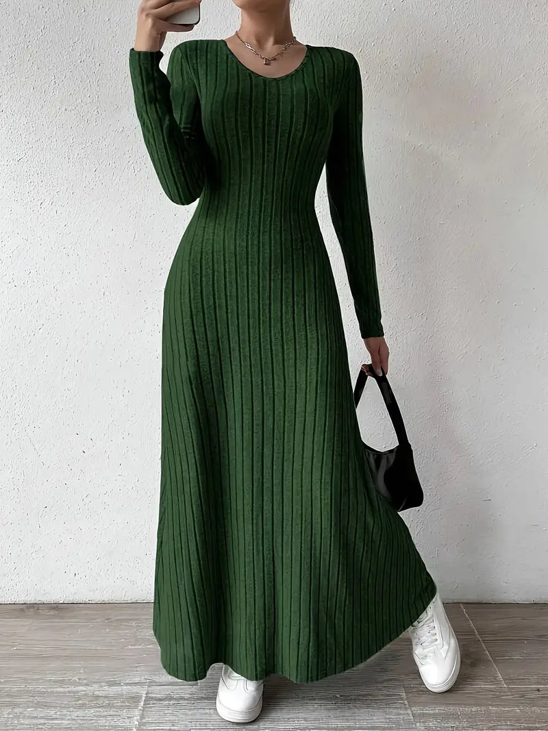 Robe longue verte à manches longues, tricotée avec motif côtelé, portée avec des baskets blanches et un sac noir. Mode féminine élégante et décontractée.