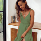 Jeune femme souriante en robe verte élégante, posant près d'une fenêtre lumineuse. Décor intérieur moderne avec cadre photo en arrière-plan.