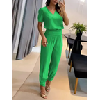 Femme en ensemble vert élégant, blouse à manches courtes et pantalon ample, posant dans un salon moderne. Mode féminine chic et tendance.