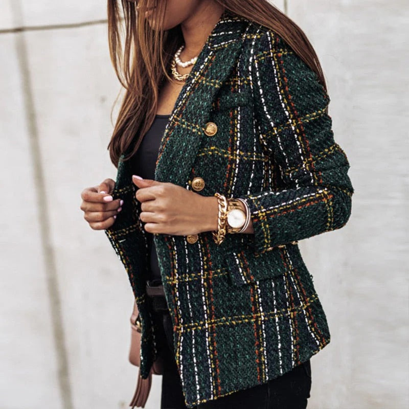 Femme portant une veste en tweed à carreaux verts avec boutons dorés, accessoirisée de bijoux dorés. Mode élégante et tendance automne-hiver.