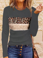 Femme portant un pull à manches longues avec motif léopard et bande beige, associé à un jean à boutons. Mode décontractée, tendance automne.