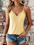 Femme portant un débardeur jaune en dentelle et un short en jean, posant devant un mur en briques. Mode estivale, tenue décontractée, accessoires bohèmes.