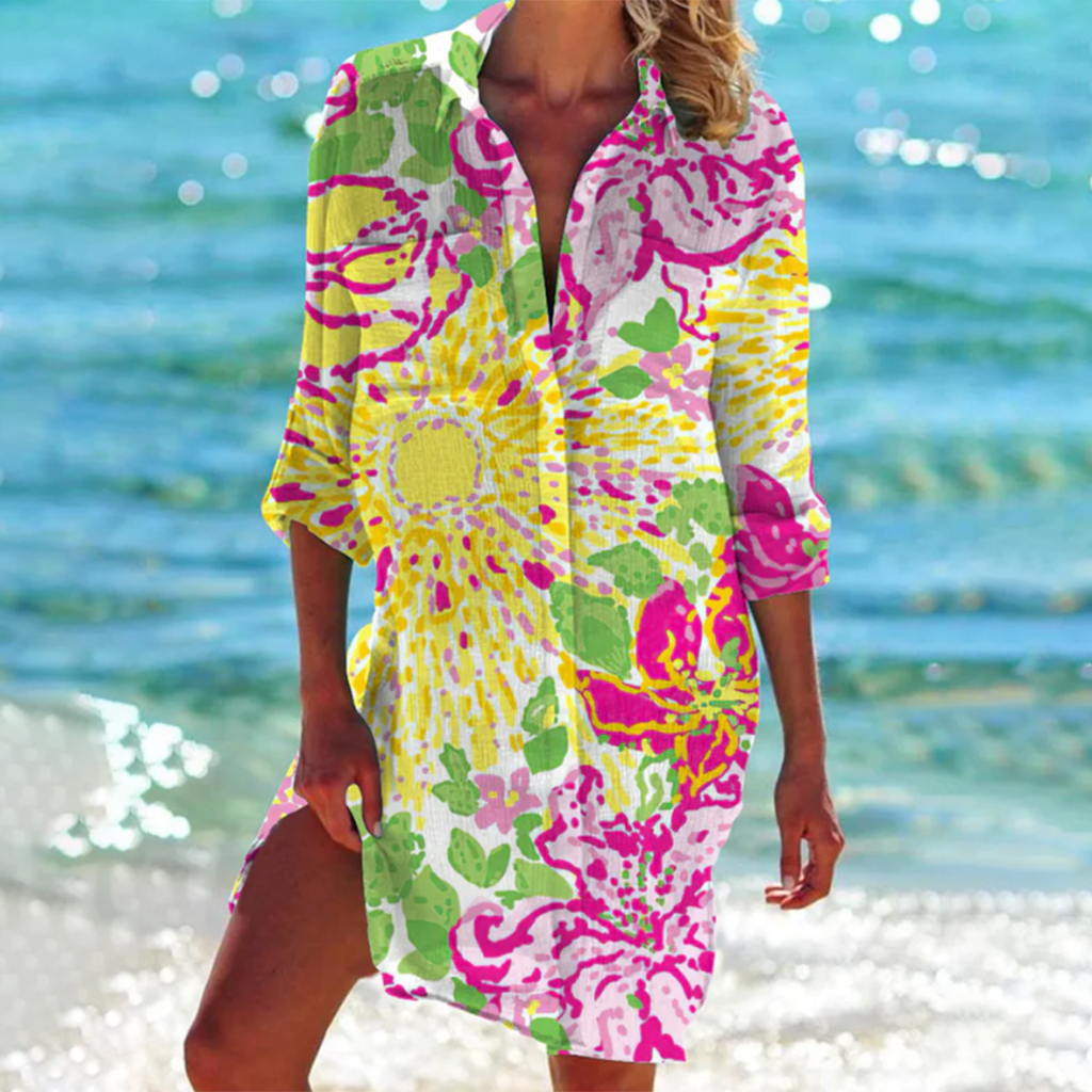 Robe de plage colorée à motifs floraux, manches longues, portée par une femme au bord de la mer. Mode estivale, tenue de plage vibrante.