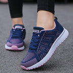 Chaussures de course bleues et roses pour femme, semelle blanche, sur route grise. Confortables et légères, idéales pour le sport et la marche.