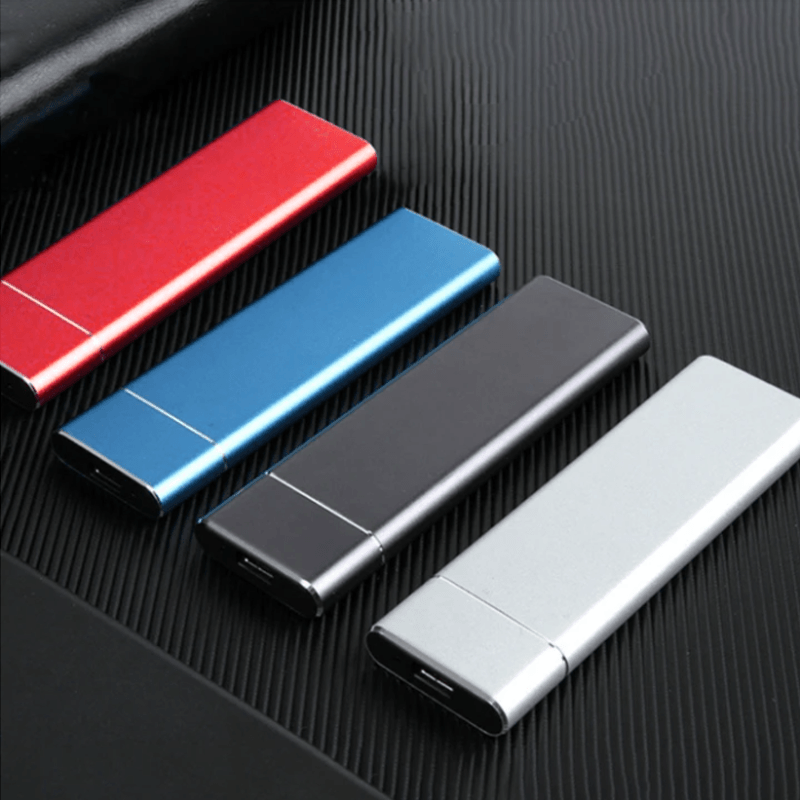 Quatre clés USB colorées (rouge, bleu, noir, argent) alignées sur une surface noire texturée, illustrant des accessoires de stockage modernes et élégants.