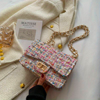 Sac à main en tweed multicolore avec chaîne dorée sur manteau blanc, livre "Matisse" et décorations dorées. Accessoire mode élégant et tendance.