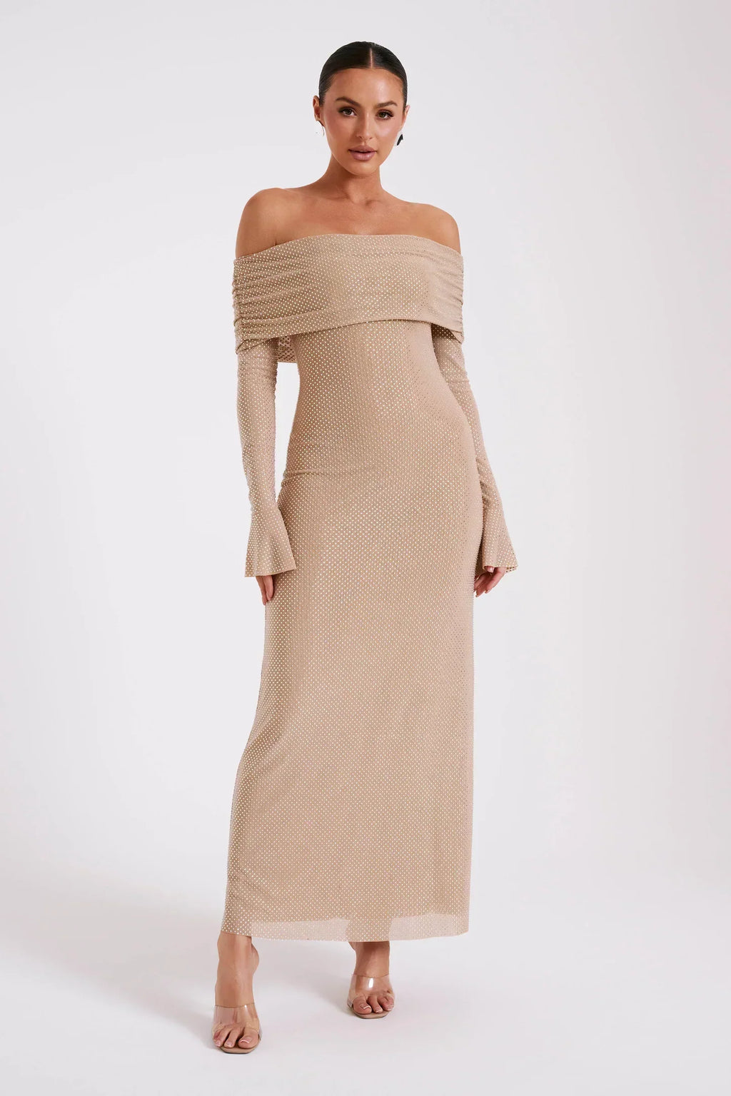 Robe longue beige à épaules dénudées, manches longues, portée par une femme. Mode élégante, tendance, tenue de soirée chic.