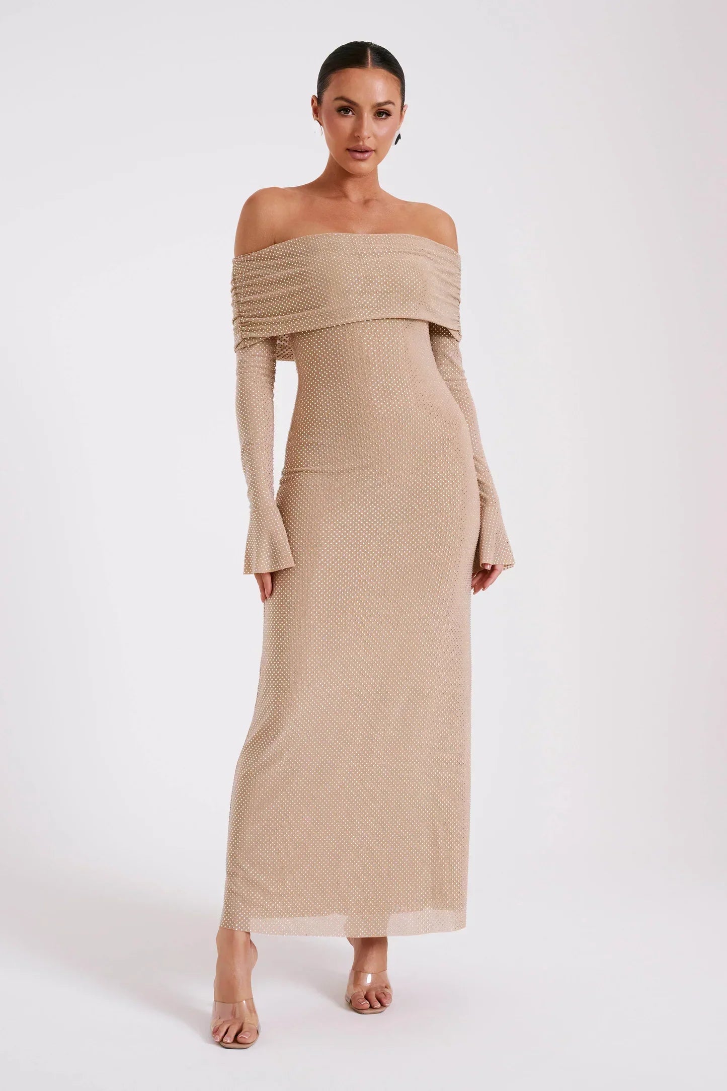 Robe longue beige à épaules dénudées, manches longues, portée par une femme. Mode élégante, tendance, tenue de soirée chic.