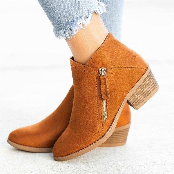 Bottines en daim marron avec talon bas, fermeture éclair latérale, portées avec un jean délavé. Chaussures tendance automne-hiver pour femmes.