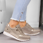 Chaussures de sport beiges pour femme, design moderne avec lacets et fermeture éclair, portées avec un jean déchiré clair, style décontracté tendance.