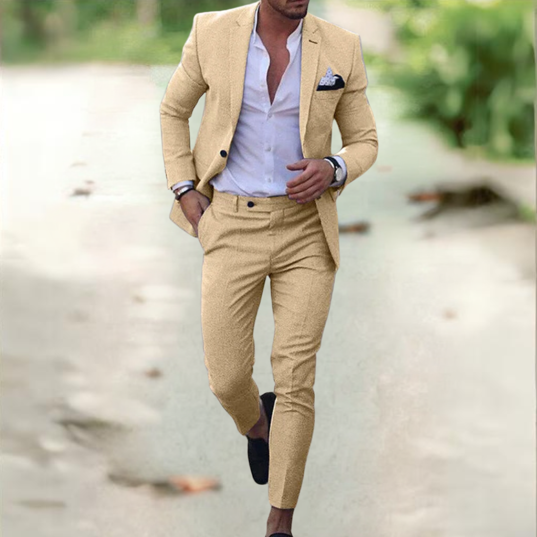 Homme en costume beige élégant, chemise blanche ouverte, marchant en extérieur. Mode masculine, style chic, tenue décontractée.