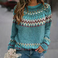 Femme portant un pull bleu à motifs nordiques, tenant un bouquet de fleurs blanches. Mode automne-hiver, style décontracté et tendance.