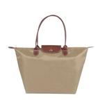 Sac à main beige en toile avec anses et rabat en cuir marron, style cabas. Accessoire mode élégant et pratique pour femme.