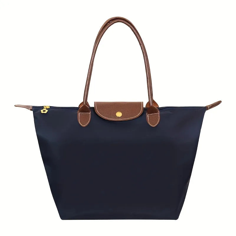 Sac à main en toile bleu marine avec poignées en cuir marron, design élégant et pratique, idéal pour le quotidien et les voyages.