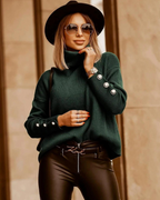 Femme élégante en pull vert à col roulé, chapeau noir et lunettes de soleil, posant avec assurance. Mode automne, style urbain chic.