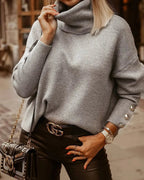 Femme portant un pull gris à col roulé, ceinture Gucci, sac à main clouté noir, pantalon en cuir, montre dorée, style automne chic urbain.