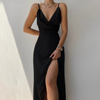Robe noire élégante avec décolleté drapé et fente haute, portée par une femme. Mode chic, soirée, tendance, style glamour.