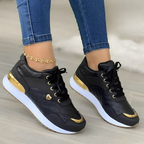 Chaussures de sport noires et dorées pour femme, avec détails métalliques, portées avec un jean ajusté. Sneakers tendance et élégantes.