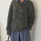 Personne portant un cardigan gris en laine sur une chemise bleue, style décontracté et élégant, mode automne-hiver, tendance vêtements superposés.