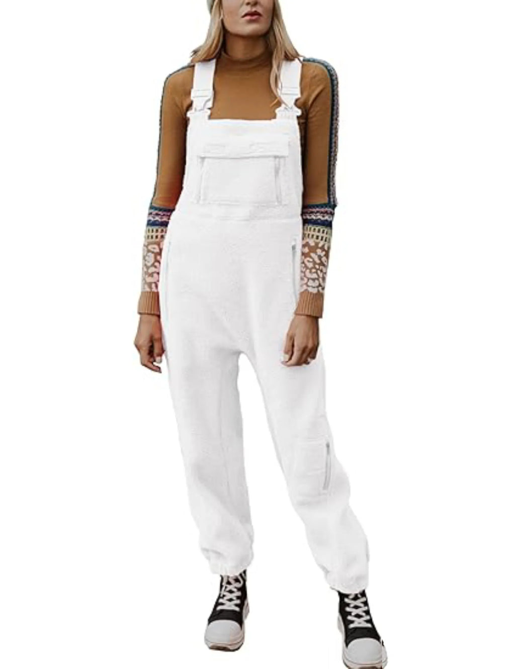 Salopette blanche femme, style décontracté, avec pull marron à manches longues motifs colorés, baskets noires et blanches. Mode tendance automne-hiver.