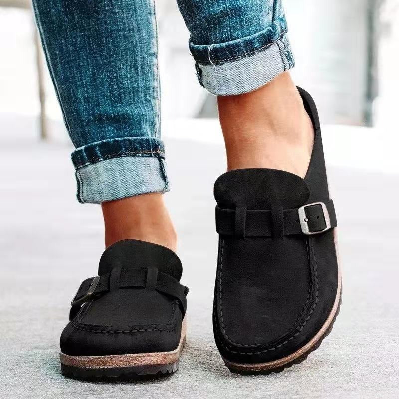Chaussures mocassins noires en daim avec boucle, portées avec un jean retroussé. Style décontracté, tendance, confort, mode urbaine.