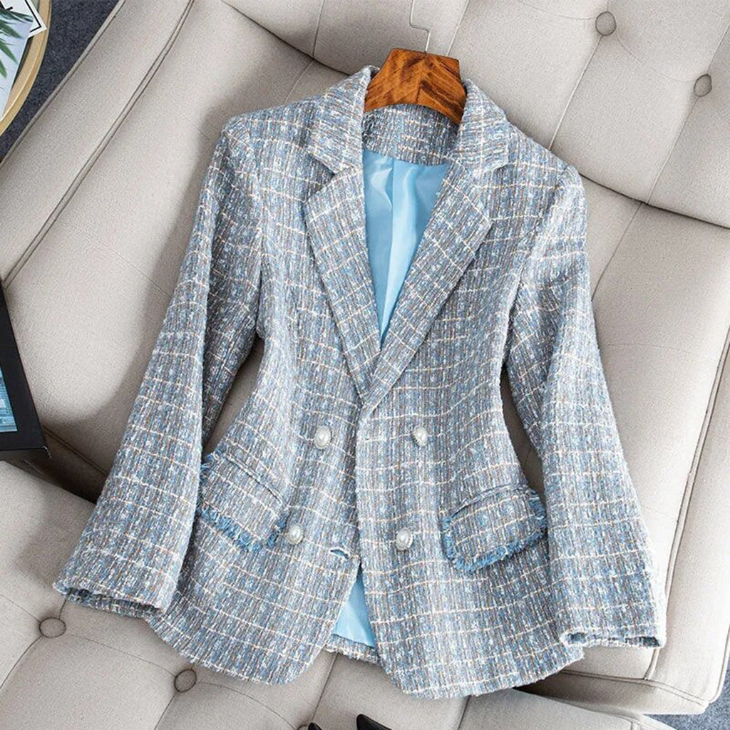 Veste en tweed bleu pour femme, élégante et chic, posée sur un fauteuil beige. Mode automne-hiver, tendance, double boutonnage.