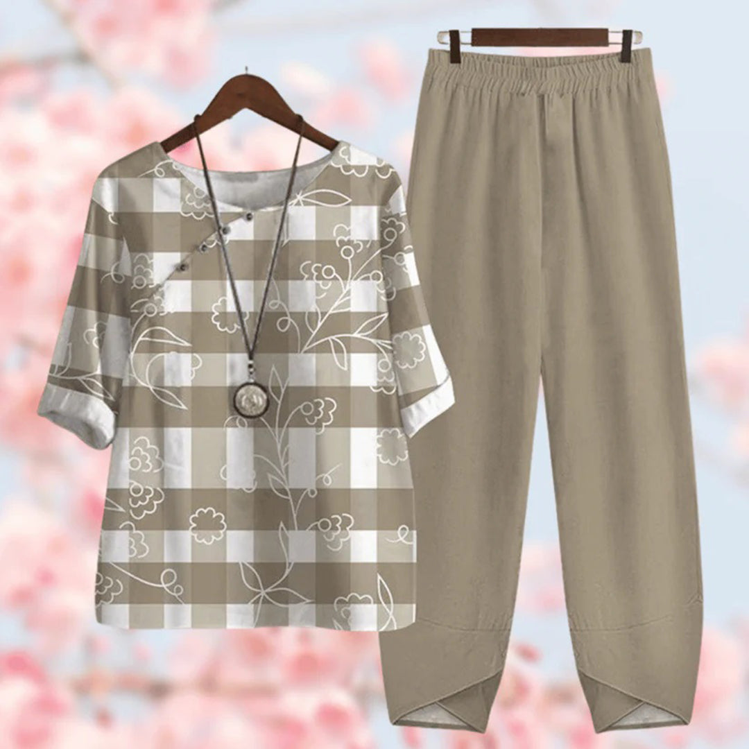 Tenue décontractée femme : chemisier à carreaux beige et blanc avec motifs floraux, collier pendentif, pantalon ample beige, fond fleuri.